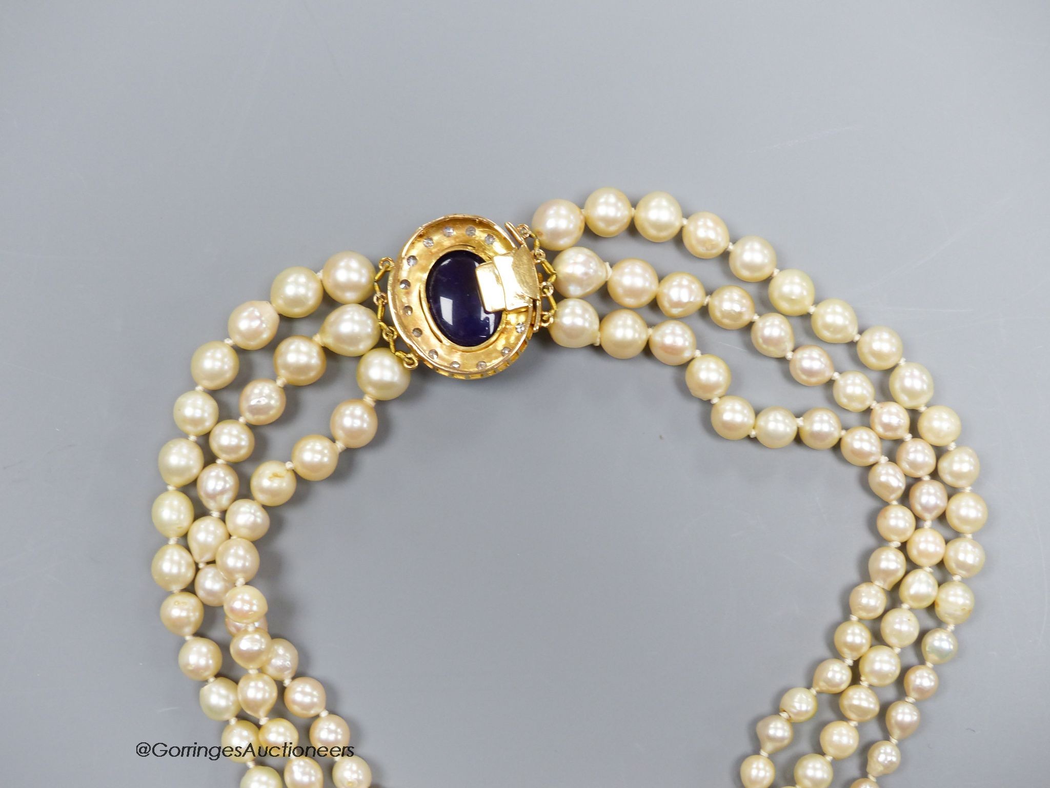 A three strand cultured pearl necklace with cabochon amethyst and diamond set 18ct gold clasp, 40cm.